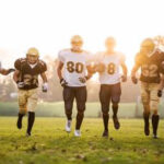 American football players running on the playing field