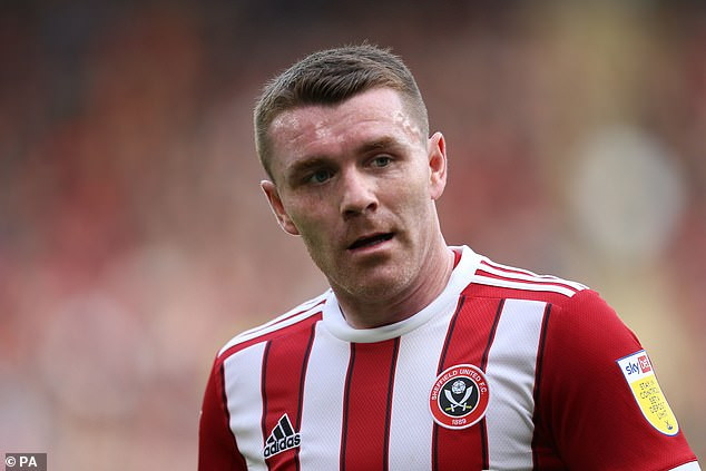 John Fleck played for Sheffield United in the Premier League, depicted in dynamic action, exemplifying the athleticism involved and the potential risks faced by professional soccer players.