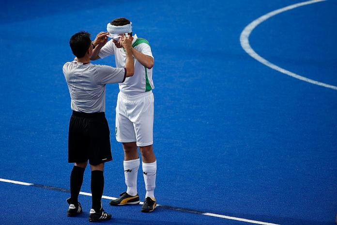 A referee inspects the eyeshades of a blind footballer to ensure compliance with Paralympic regulations