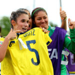 Daniela Montoya and Sandra Sepulveda celebrate a goal by holding up a Melissa Ortiz jersey.