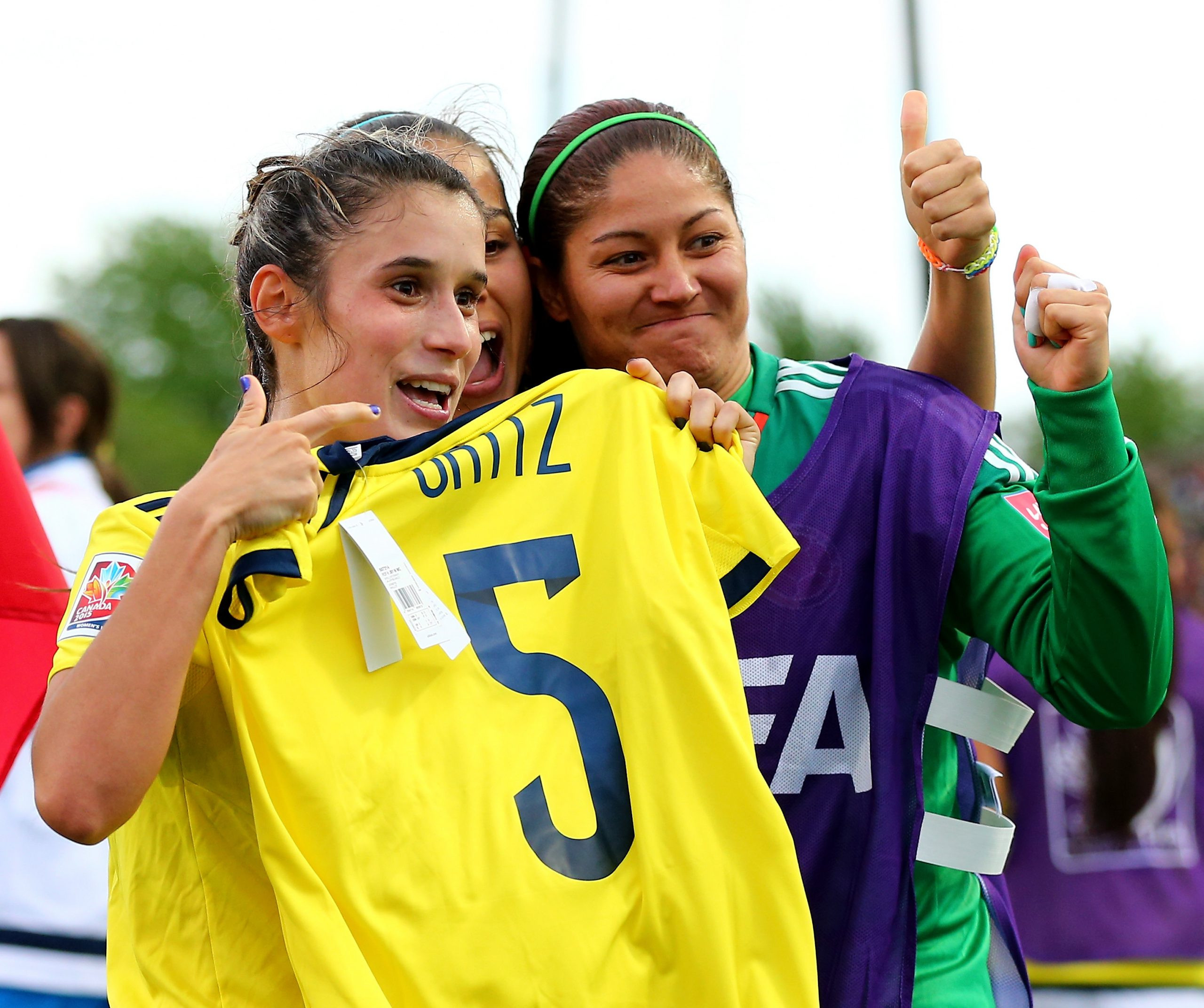 Daniela Montoya and Sandra Sepulveda celebrate a goal by holding up a Melissa Ortiz jersey.