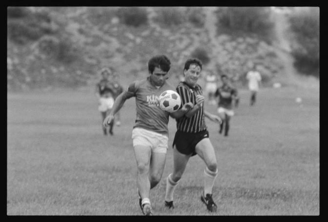 Black and white photograph of 2 soccer players kicking soccer ball