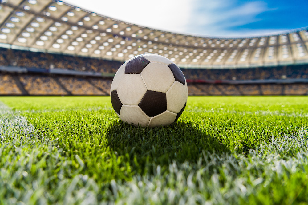 Soccer or football on grass field in middle of stadium
