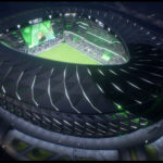 Aerial view of an illuminated modern stadium at night with a soccer match in progress.
