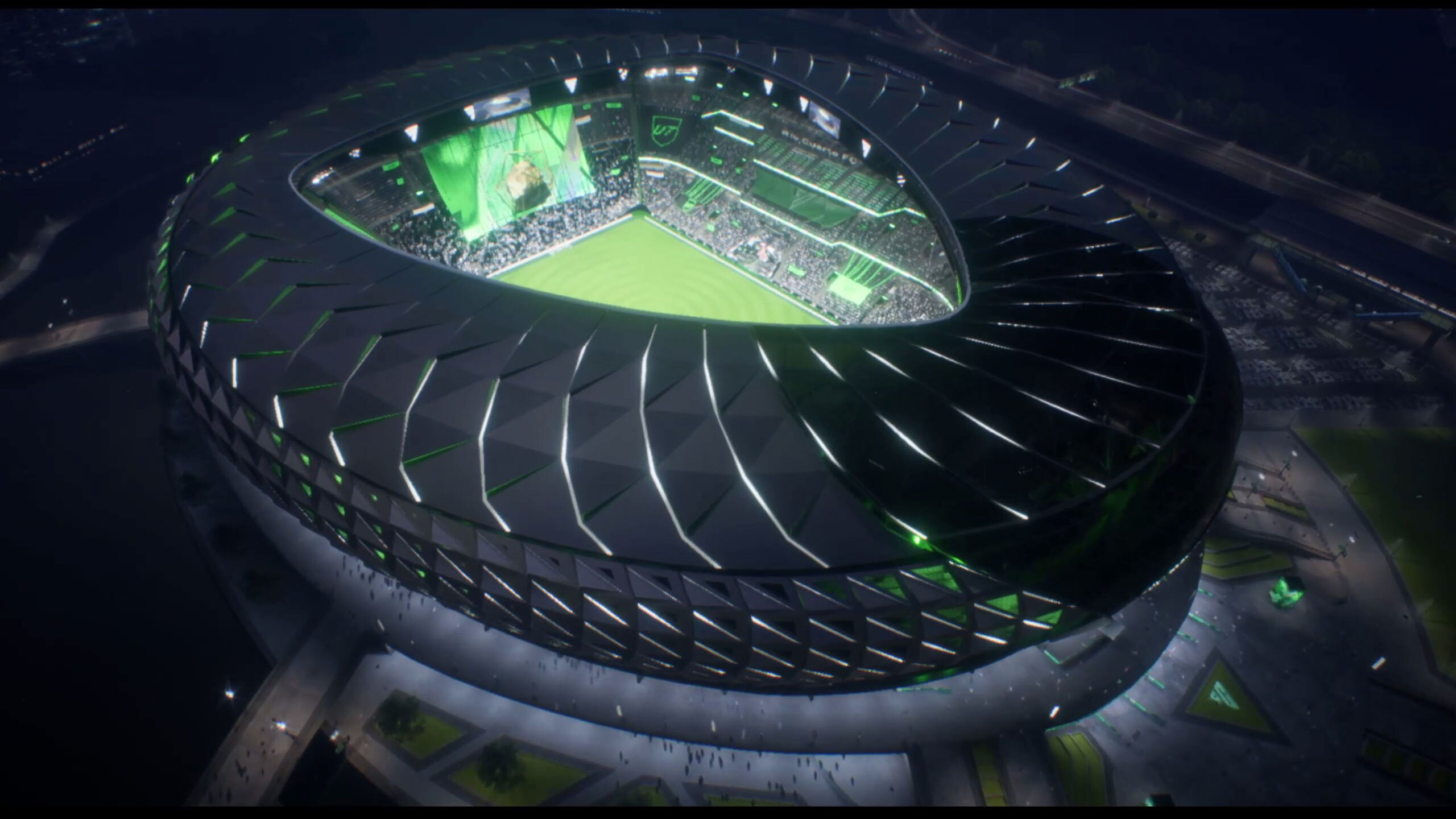 Aerial view of an illuminated modern stadium at night with a soccer match in progress.