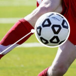 Player in red jersey using first touch, one of the basic fundamental football skill