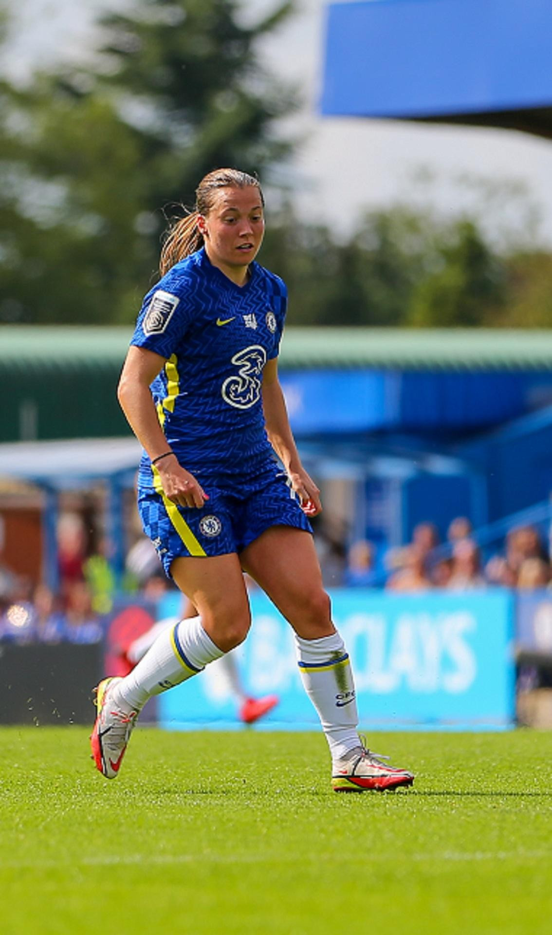 A football player in a blue team uniform runs on the pitch. 