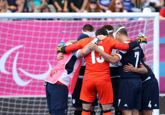 A huddle of five-a-side football players gather to strategize during a break in the game