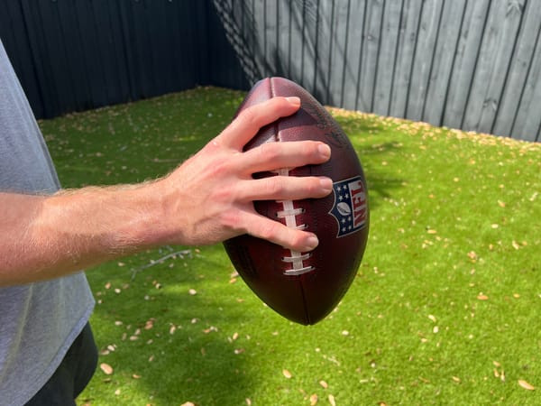 Ring finger over the second lace, pinky over the fifth, demonstrating quarterback grip