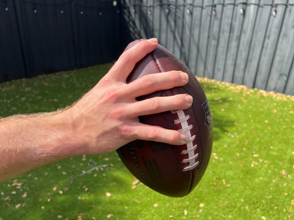 Ring finger over the first lace and pinky under the fourth for secure football hold
