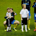 Footballer Kim Kallstrom hugs a young mascot named Max, showcasing kindness and empathy
