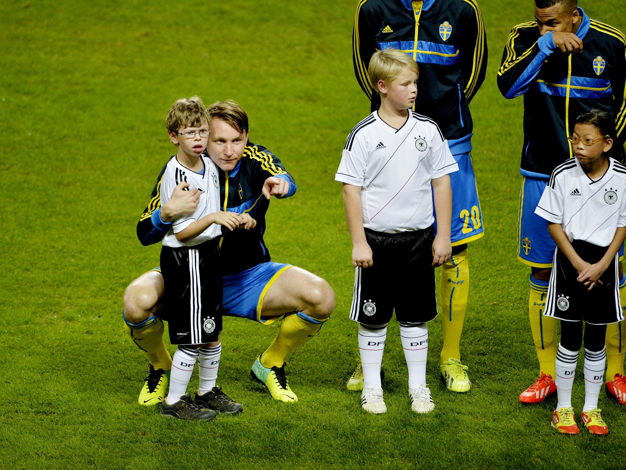 Footballer Kim Kallstrom hugs a young mascot named Max, showcasing kindness and empathy