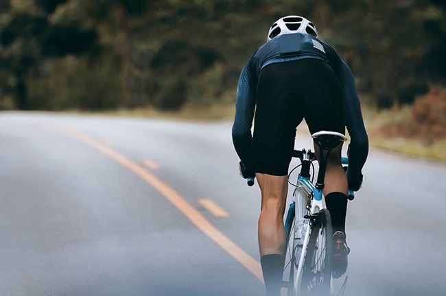 A middle-aged man cycling on an open road.