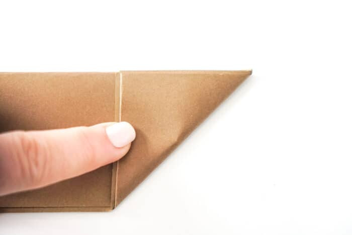 Folding paper in half lengthwise to create a paper football