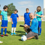 A group of children receive instructions for a grassroots football coach.