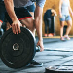 A fitness coach guiding an athlete through a weightlifting exercise