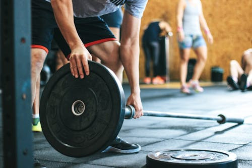 A fitness coach guiding an athlete through a weightlifting exercise