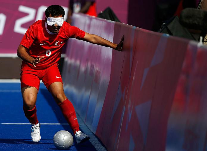 A Turkish blind footballer uses the side boards for guidance during a five-a-side match