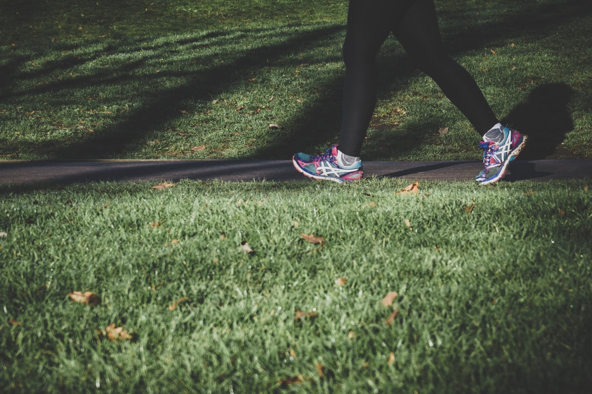 A person enjoying a brisk walk in the park, demonstrating active recovery to promote blood flow and reduce muscle stiffness