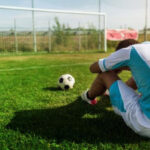 Tired soccer player resting on field