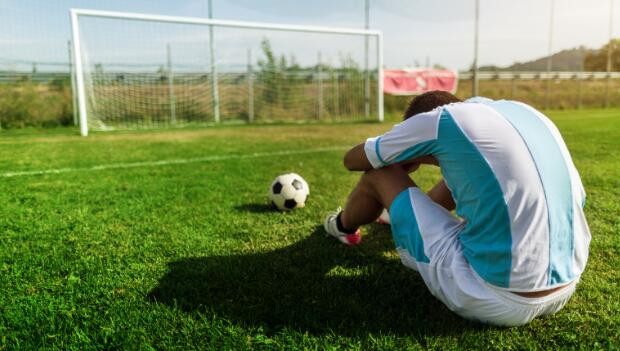 Tired soccer player resting on field