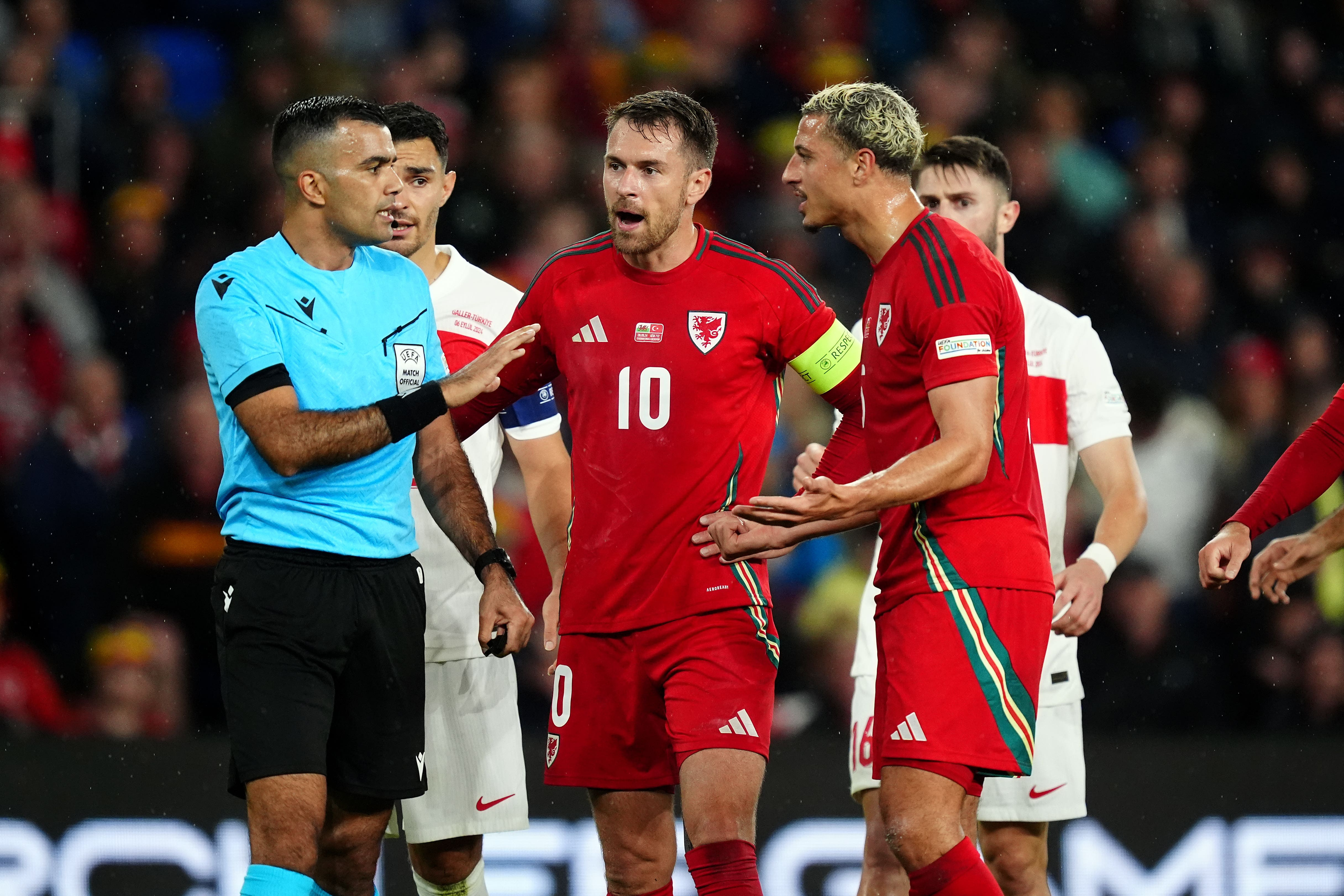 Referee Rohit Saggi speaks to Wales pair Aaron Ramsey and Ethan Ampadu in the goalless Nations League draw with Turkey