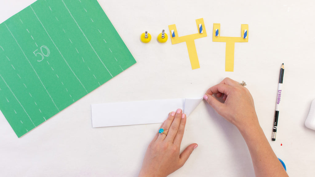 Folding a corner of the paper strip to create a triangle shape
