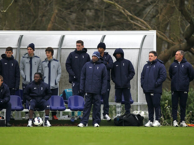 Scouts observing a football match from the sidelines, assessing player performance and potential.