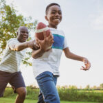 A boy and his dad have fun playing football in the backyard.