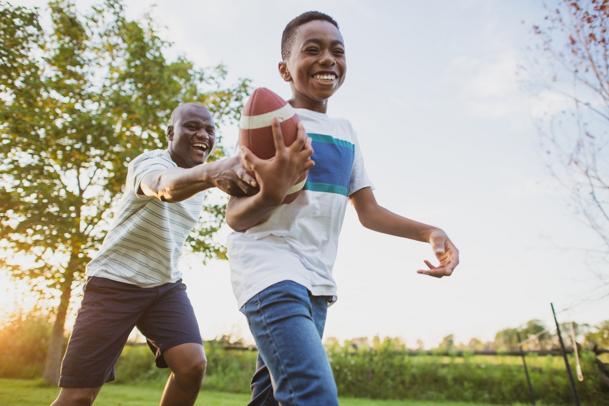 A boy and his dad have fun playing football in the backyard.