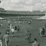 A black and white picture of people walking towards the Shoe, which appears to be full for game day