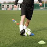 Man dribbling football through cones