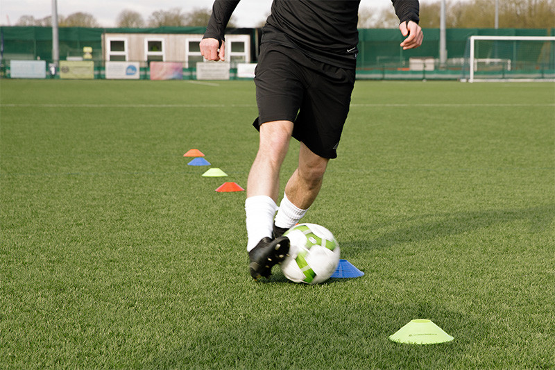Man dribbling football through cones