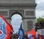 PSG parading down towards the Arc de Triomphe on an open-top bus, fans holding PSG flags