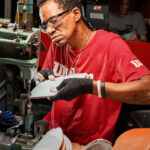 A factory worker sews football panels together.