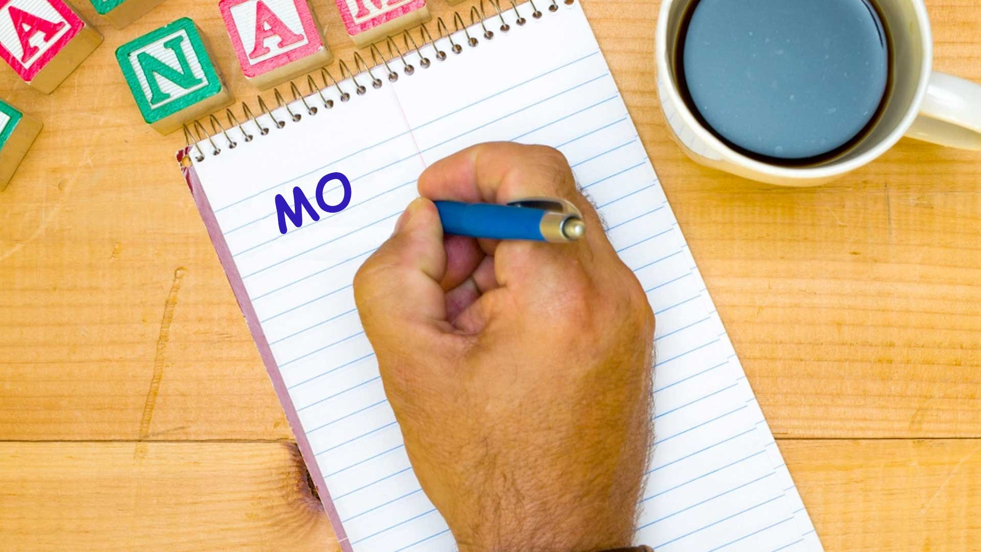 A man writing Mo on a notepad