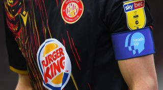 Heads Up armband during the Exeter City vs Stevenage match, highlighting the ketchup and mustard kit colors