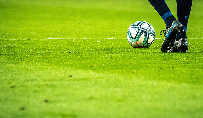 Playing football on a smooth grass pitch.