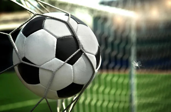 Football in motion flying towards the goal net