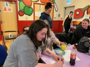 Young woman writing a leaf for the kindness and compassion tree.